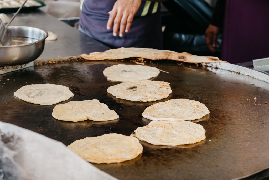 Roti prata being cooked on a hawker's hot plate in Singapore.
